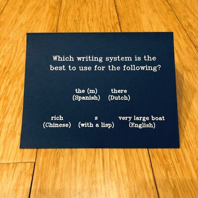 A folded card with the following written on it: Which writing system is the best to use for the following? the (m) (Spanish) there (Dutch) rich (Chinese) s (with a lisp) very large board (English)